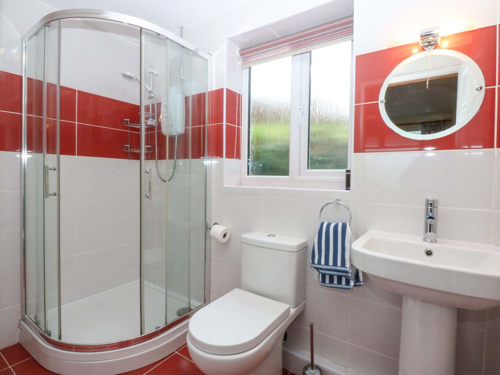 A bathroom featuring a shower, toilet, and sink at Min Y Traeth Bull Bay