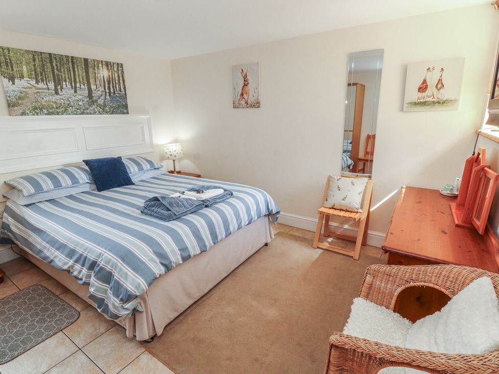 A bedroom with a bed and mirror at Piggery Cottage in Wigton