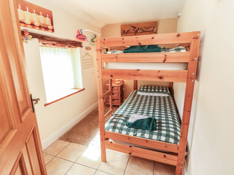 A bedroom with a bunk bed and a window at Piggery Cottage in Wigton