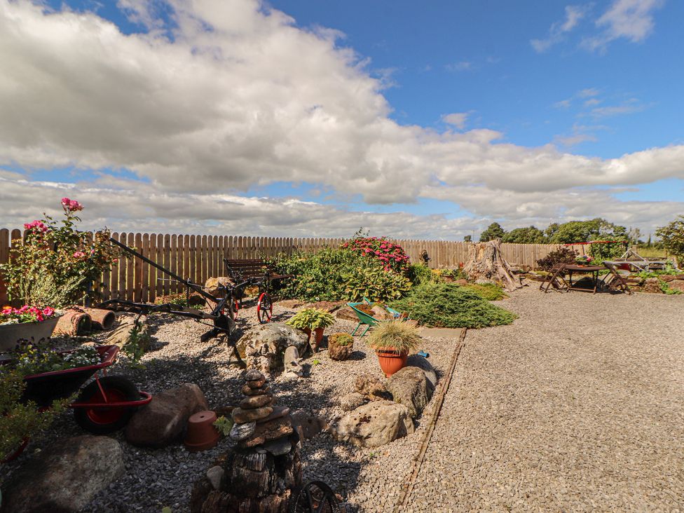 A garden with gravel path and flowers at Piggery Cottage in Wigton