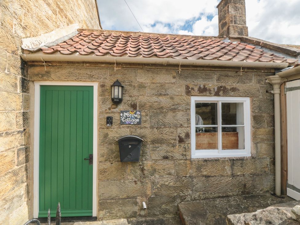 An entrance with a green door and stone wall at 1 Brow Cottages in Green End near Goathland