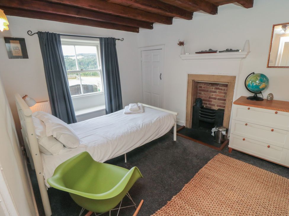 A bedroom with a bed, globe, and fireplace at 1 Brow Cottages in Green End near Goathland