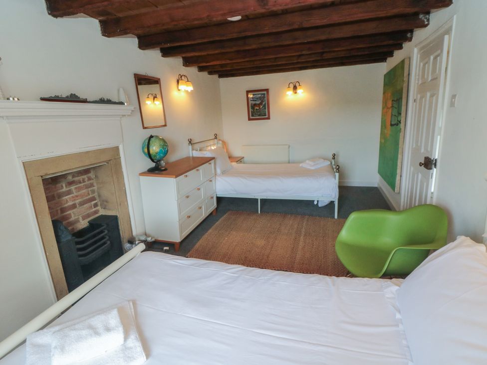 A bedroom with two beds and a fireplace at 1 Brow Cottages Green End near Goathland