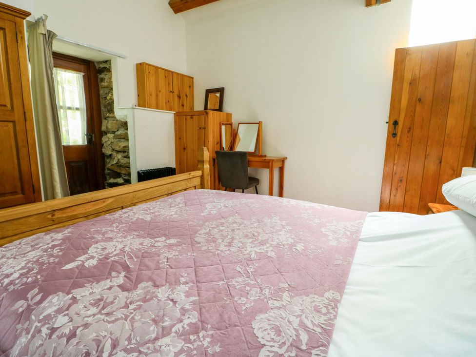 A bedroom with a bed and dresser at Bythyn Ddol Hafod in Capel Curig
