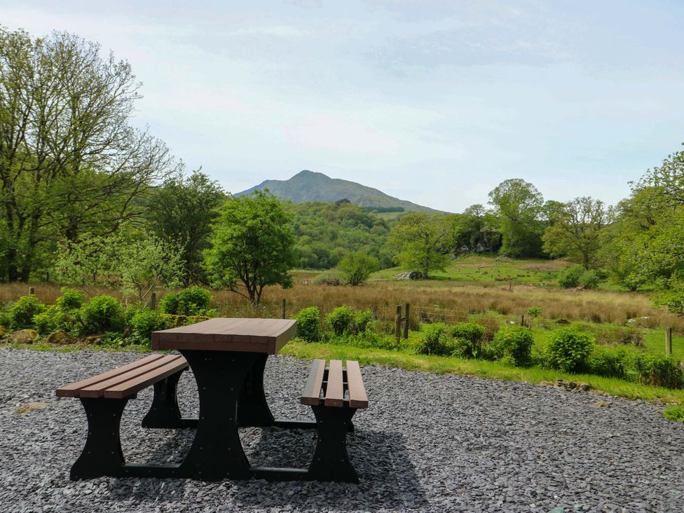 A picnic table with benches in an outdoor area at Bythyn Ddol Hafod in Capel Curig