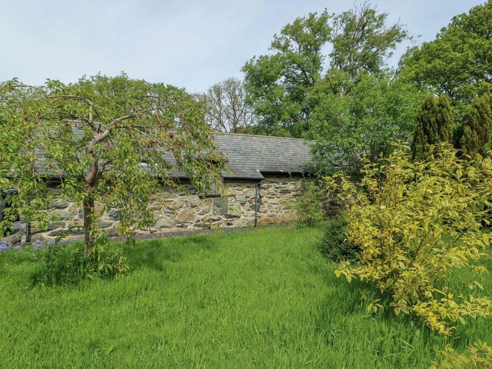 A garden with a stone wall and trees at Bythyn Ddol Hafod in Capel Curig