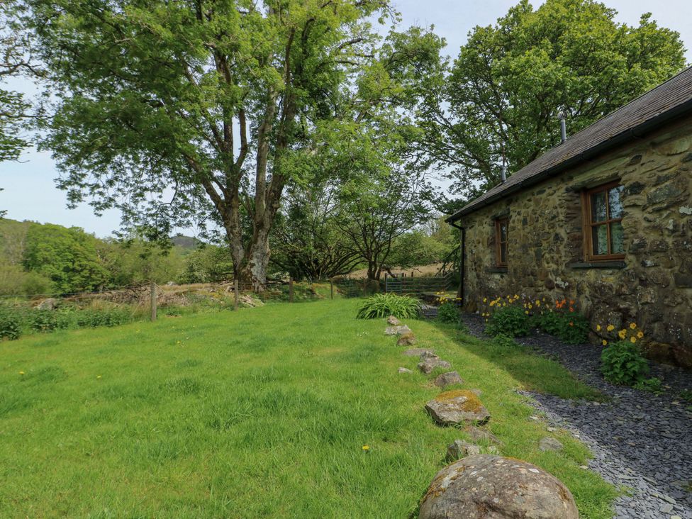 A garden with trees and a stone building at Bythyn Ddol Hafod Capel Curig