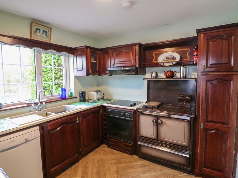 A kitchen with wooden cabinets and appliances at The Farmhouse in Dunmanway, County Cork