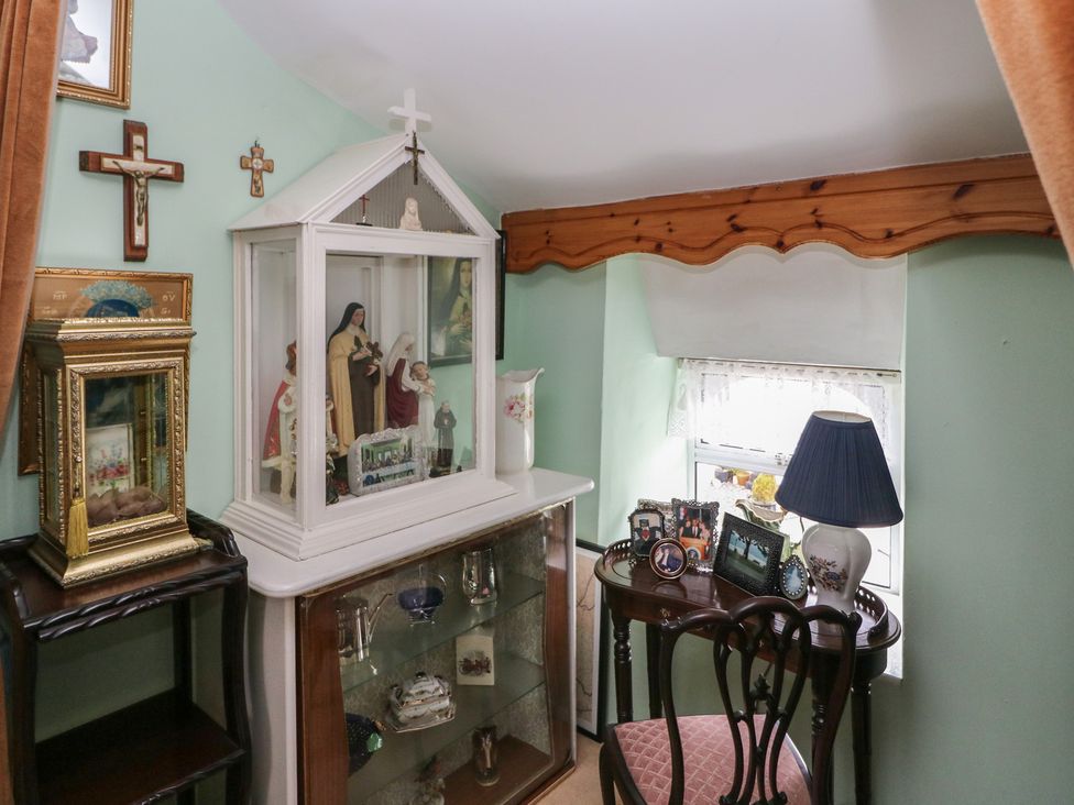 A snug with statues in a cabinet and a table with pictures at The Farmhouse in Dunmanway, County Cork