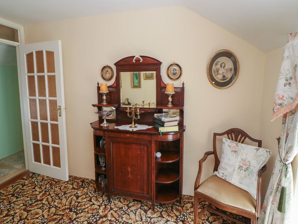 A table with a mirror and books next to a chair at The Farmhouse in Dunmanway, County Cork