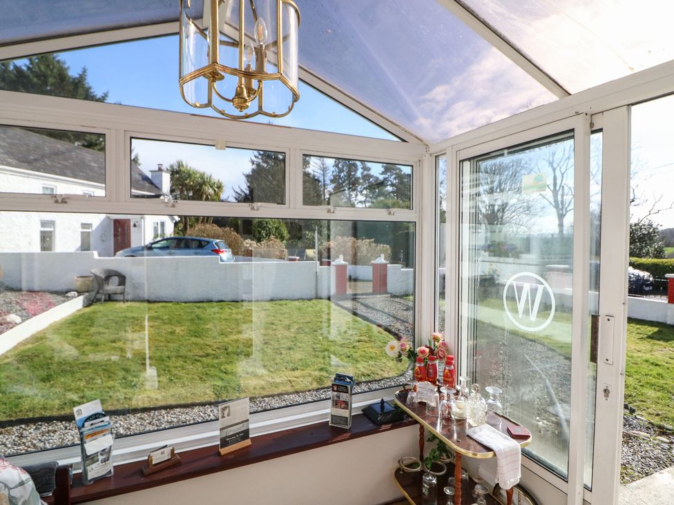 A conservatory with glass windows and a table at The Farmhouse in Dunmanway, County Cork