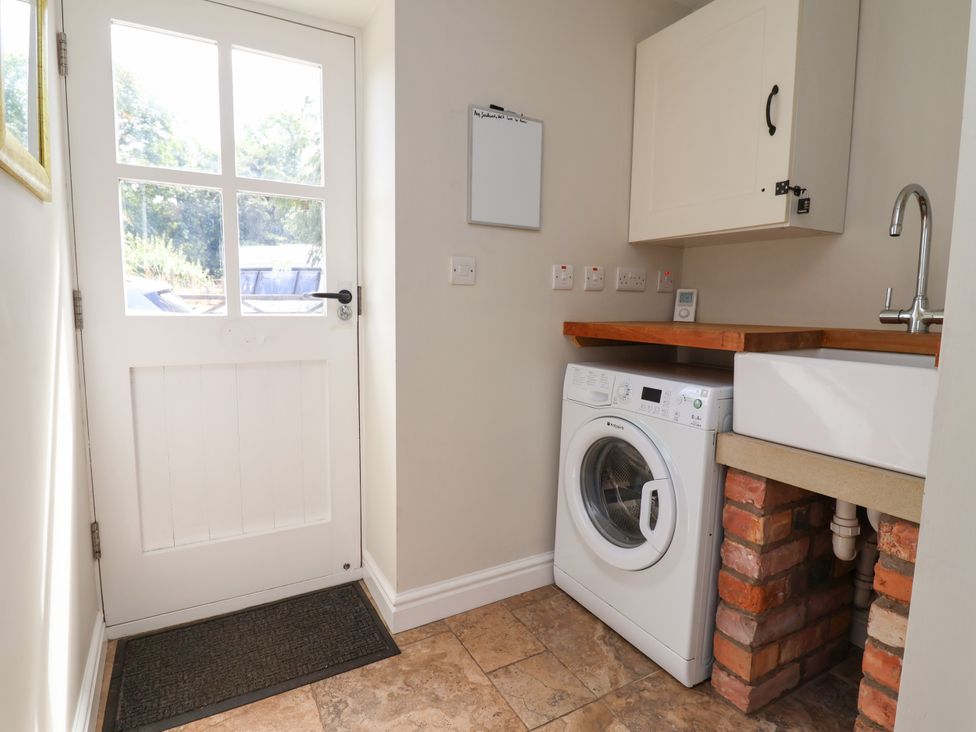 A utility room with a washing machine and sink at The Lambing Shed in Dyserth near Prestatyn