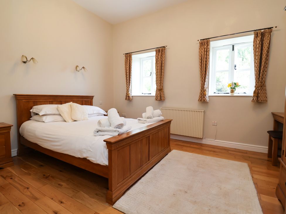 A bedroom with a bed and two windows at The Lambing Shed in Dyserth near Prestatyn