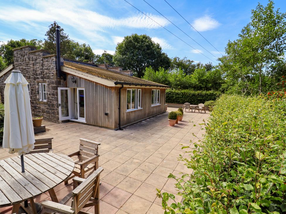An outdoor area with a house, table, chairs, and plants at The Lambing Shed Dyserth near Prestatyn