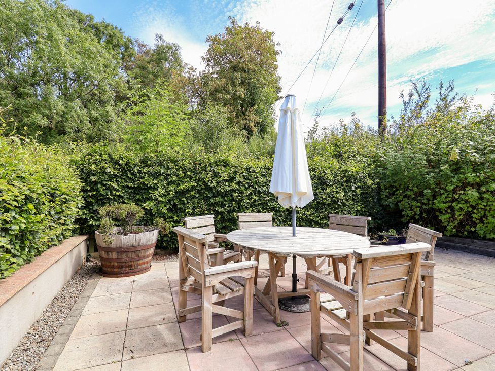A garden with a round table and chairs under an umbrella at The Lambing Shed Dyserth near Prestatyn