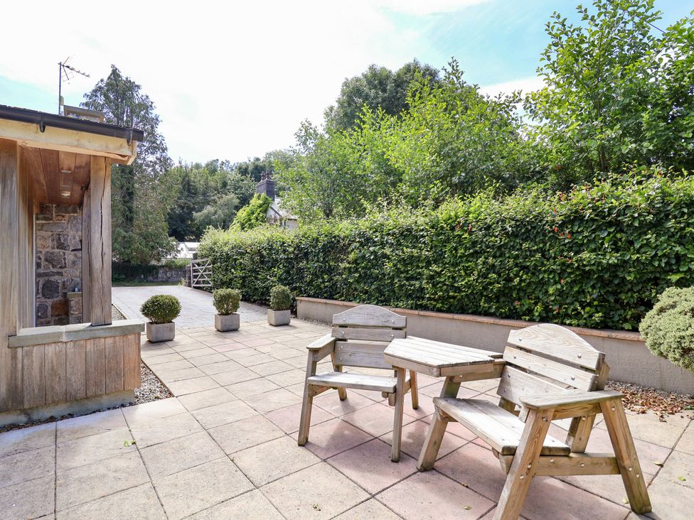 A garden with wooden chairs and a table at The Lambing Shed Dyserth near Prestatyn