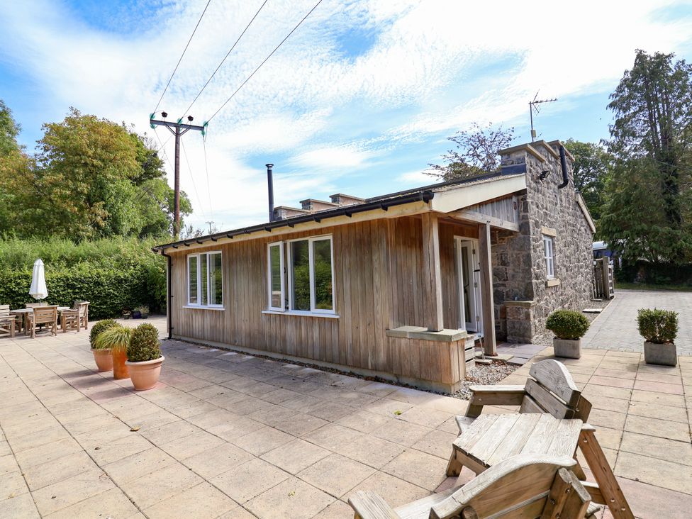 An outdoor view of a wooden building and patio area at The Lambing Shed Dyserth near Prestatyn