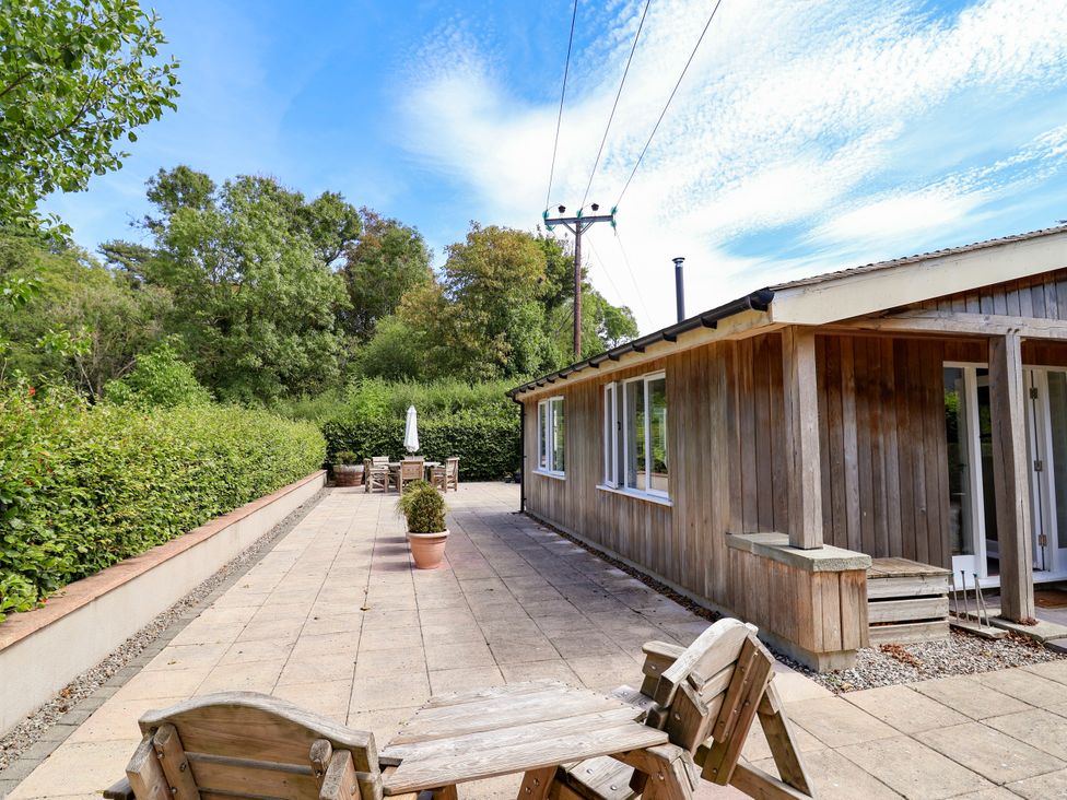 An outdoor patio area with a wooden building and seating at The Lambing Shed in Dyserth near Prestatyn
