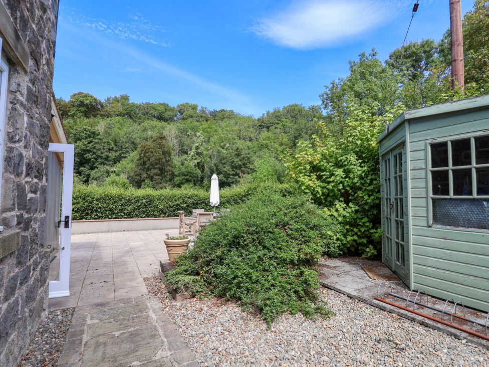 An outdoor area with a patio table and green shed at The Lambing Shed Dyserth near Prestatyn