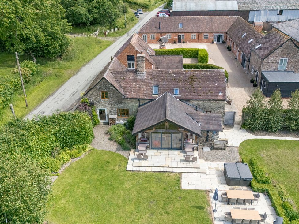 An outdoor view of a house with a patio and garden at The Olde Cowshed in Westhope near Church Stretton