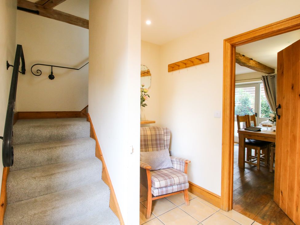 A hallway with a staircase and a chair at The Olde Cowshed near Church Stretton