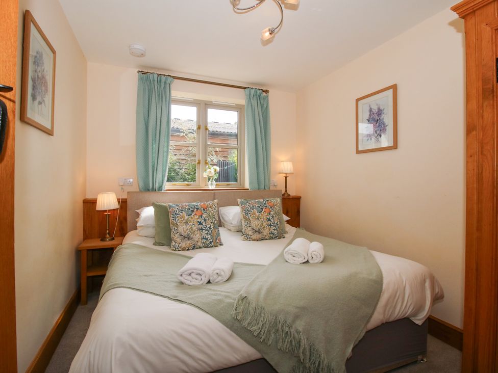 A bedroom with a bed and nightstand at The Olde Cowshed in Westhope near Church Stretton