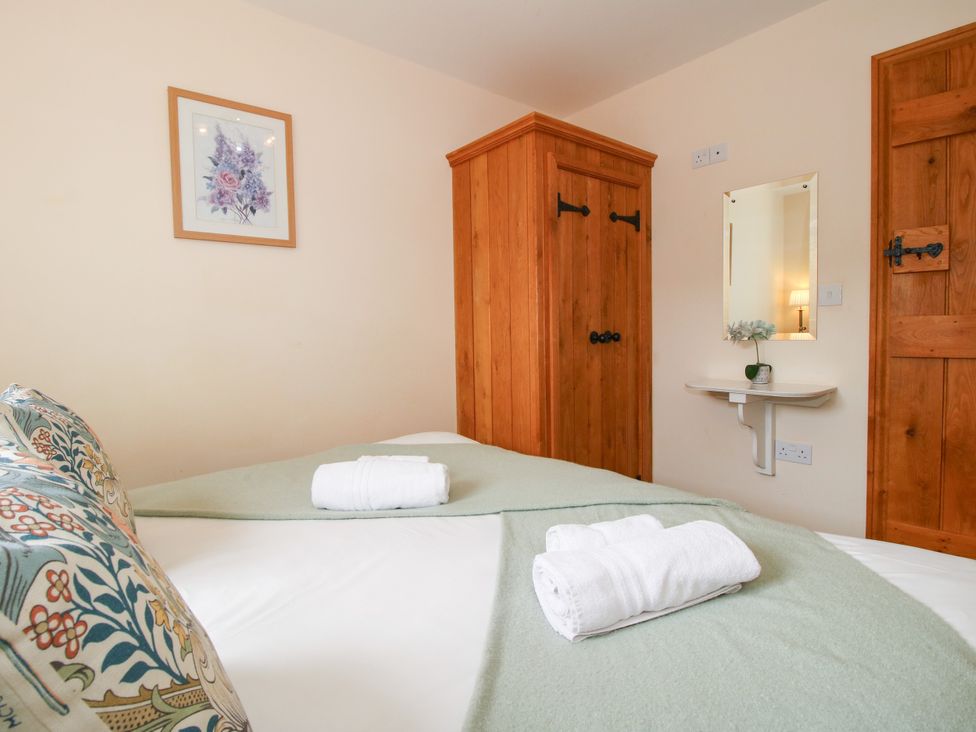 A bedroom with a bed and wooden wardrobe at The Olde Cowshed near Church Stretton