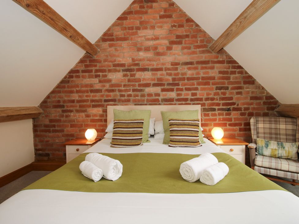 A bedroom with a bed and bedside table at The Olde Cowshed near Church Stretton