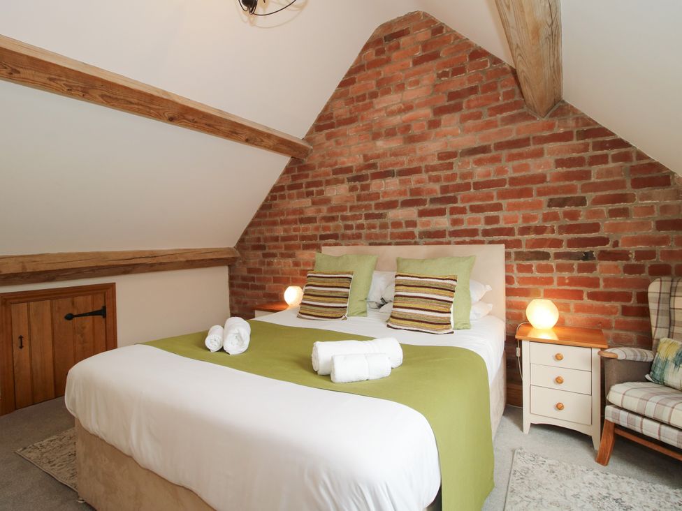A bedroom with a bed and nightstand at The Olde Cowshed in Westhope near Church Stretton