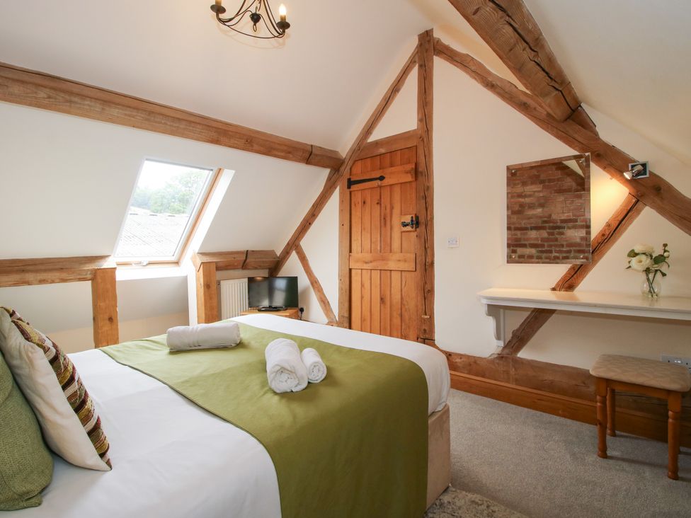 A bedroom with a bed and wooden features at The Olde Cowshed in Westhope near Church Stretton