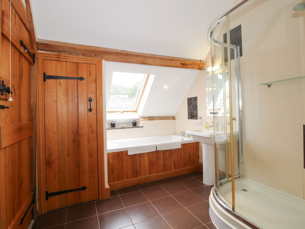 A bathroom with a bathtub and shower at The Olde Cowshed in Westhope near Church Stretton