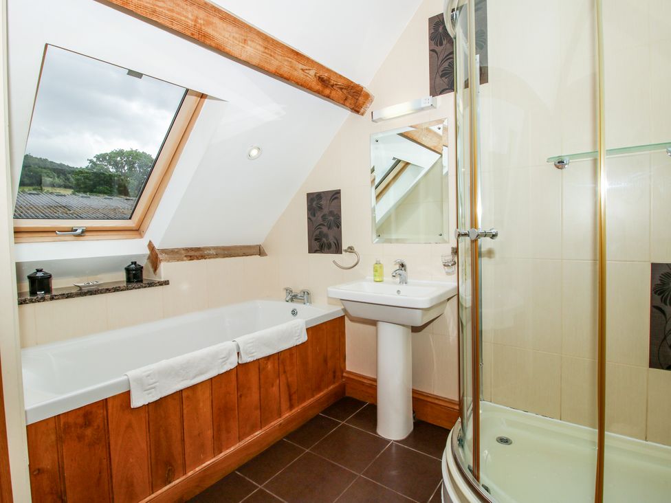 A bathroom with a bathtub, shower, and sink at The Olde Cowshed in Westhope near Church Stretton