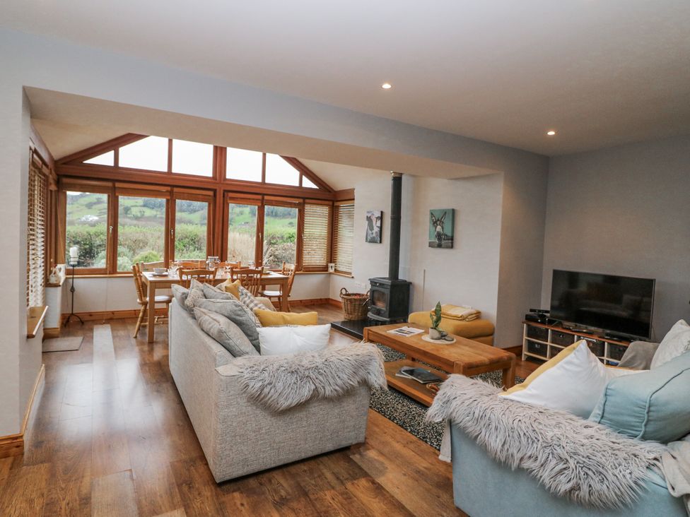 A living room with a dining area and large windows at Lough Cluhir Cottage in Union Hall, County Cork