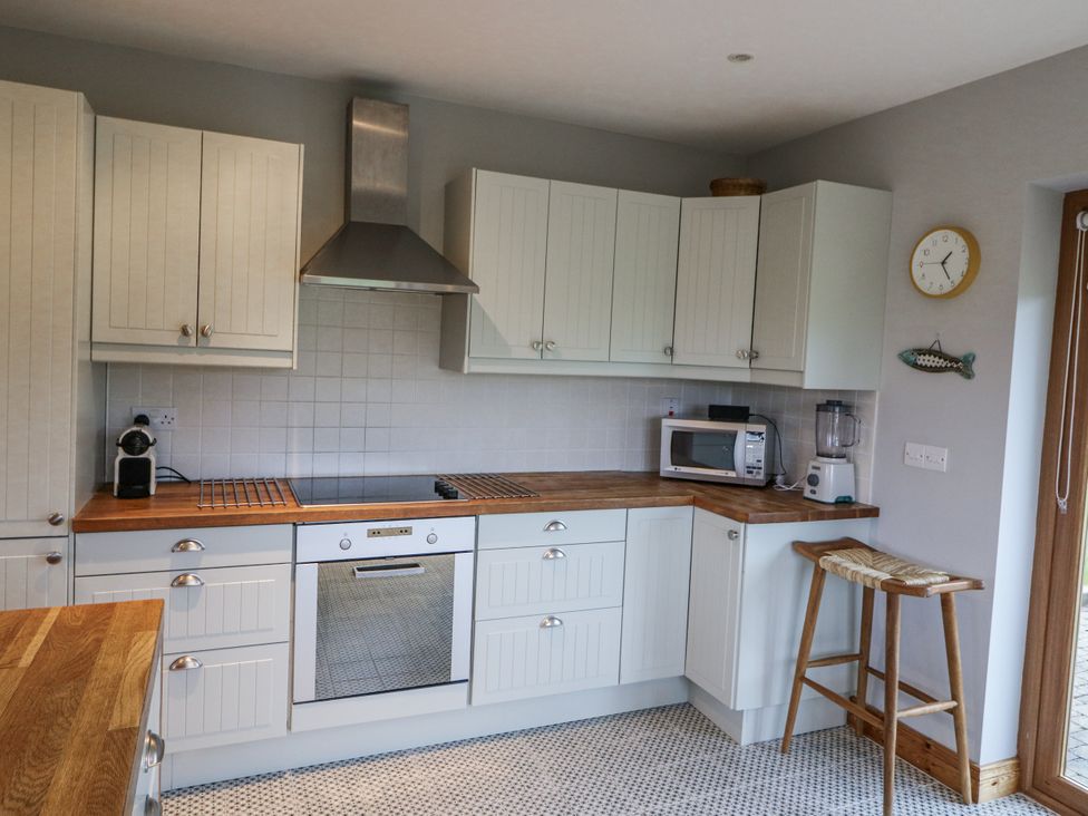 A kitchen with cabinets and appliances at Lough Cluhir Cottage in Union Hall, County Cork