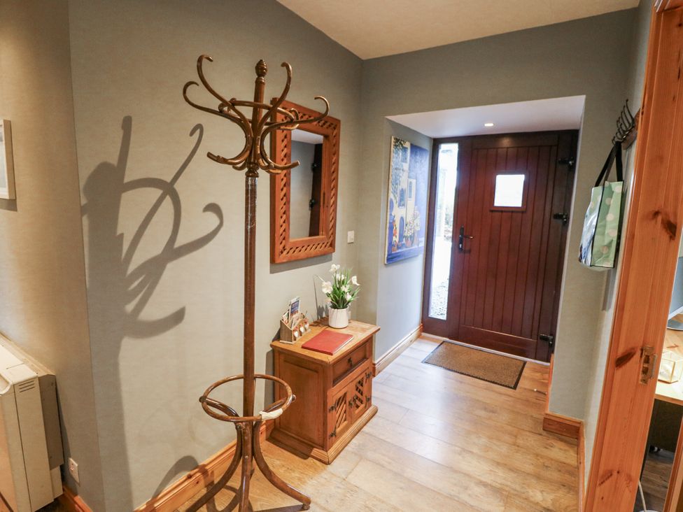 A hallway with a coat rack and a small table at Lough Cluhir Cottage, Union Hall, County Cork