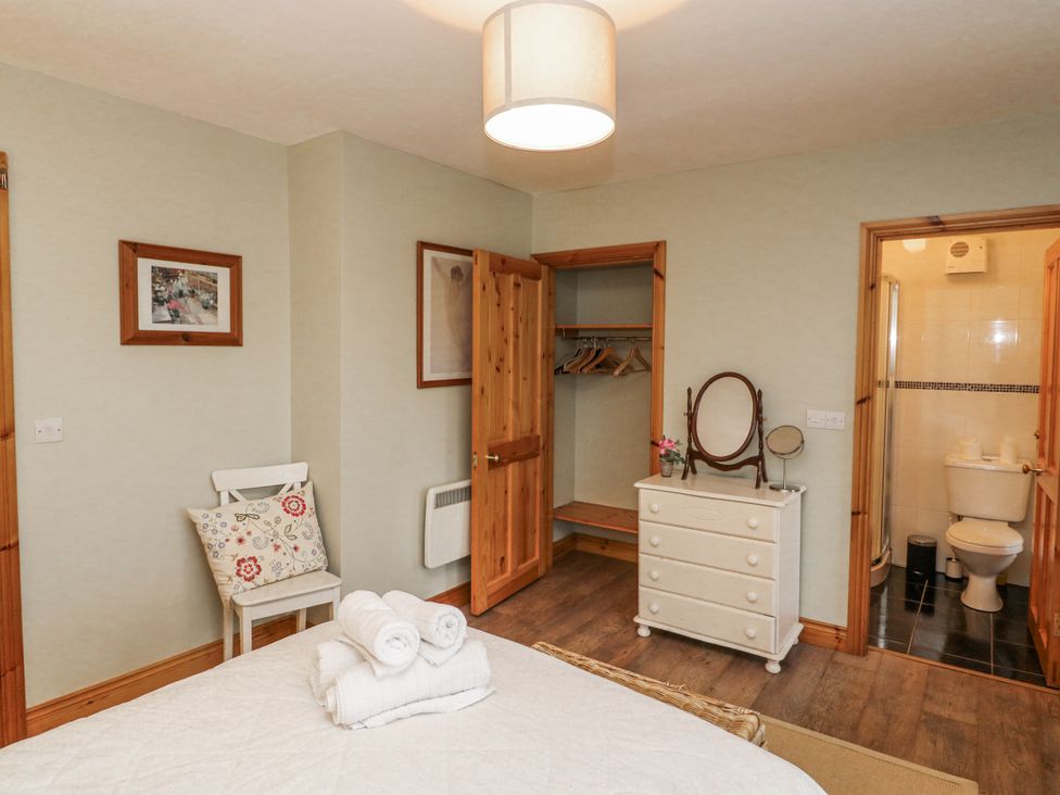 A bedroom with a bed, dressing table, and wardrobe at Lough Cluhir Cottage, Union Hall, County Cork