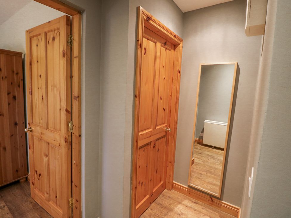 A hallway with wooden doors and a mirror at Lough Cluhir Cottage, Union Hall, County Cork