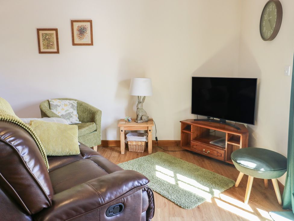 A living room with a tv and sofa at Lily Cottage in Caeathro near Caernarfon