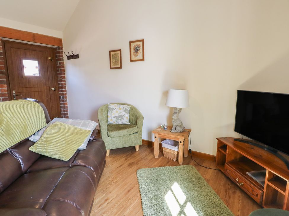 A living room with a sofa and television at Lily Cottage in Caeathro near Caernarfon