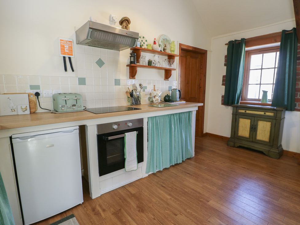 A kitchen with appliances and wooden furniture at Lily Cottage Caeathro near Caernarfon