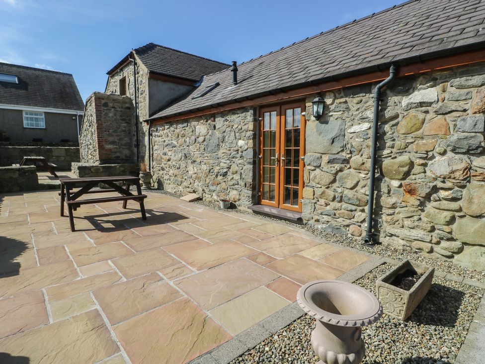 An outdoor area with a stone wall and table at Lily Cottage in Caeathro near Caernarfon