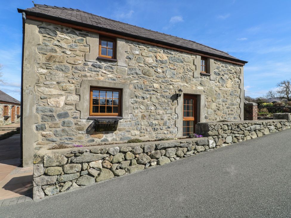 A stone wall with a door and windows at Bluebell Cottage Caeathro near Caernarfon