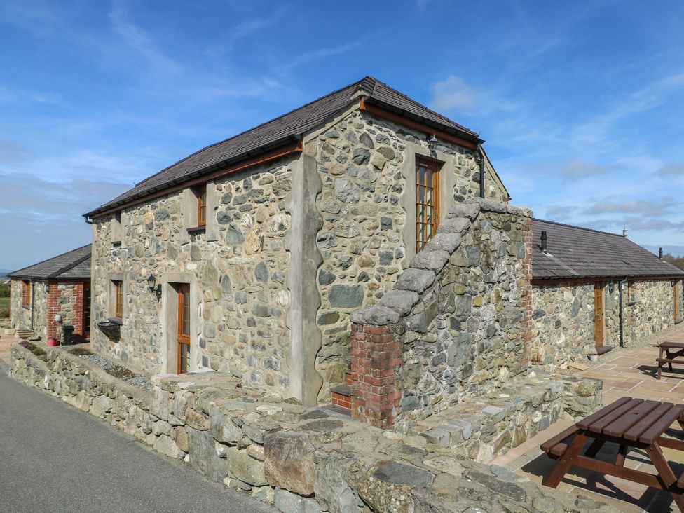 A stone building with a staircase and outdoor seating at Bluebell Cottage in Caeathro near Caernarfon