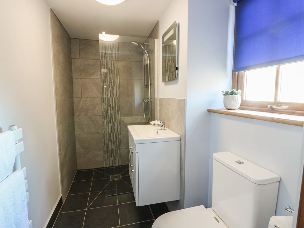 A bathroom with shower, vanity unit, and toilet at Bluebell Cottage in Caeathro near Caernarfon