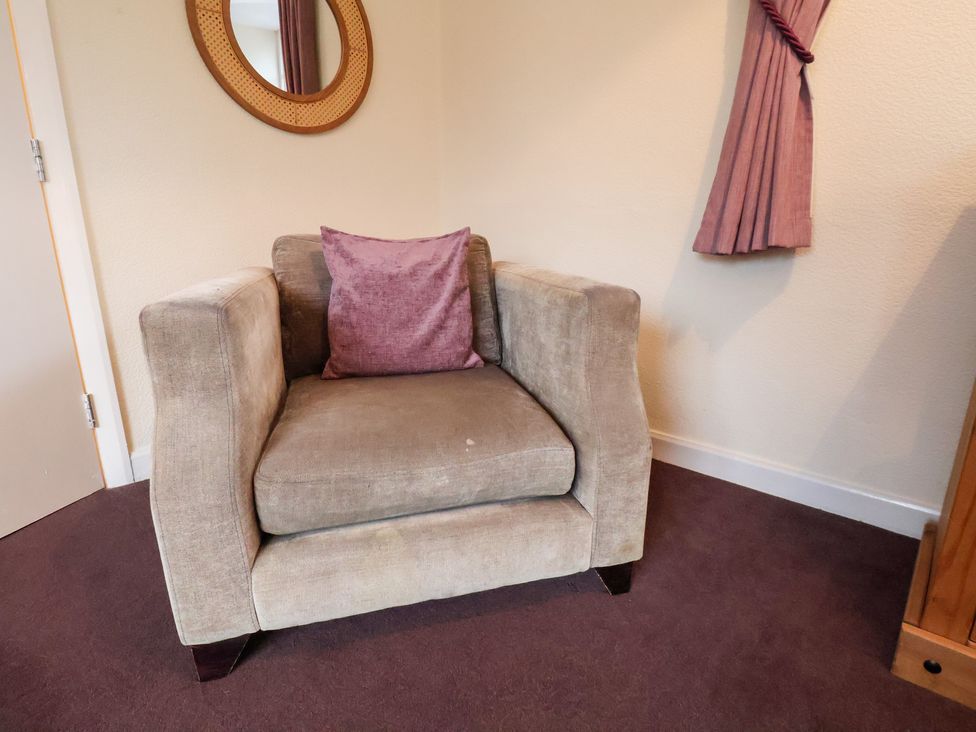 A sitting room with an armchair and cushion at The Lodge in Snainton near Scarborough