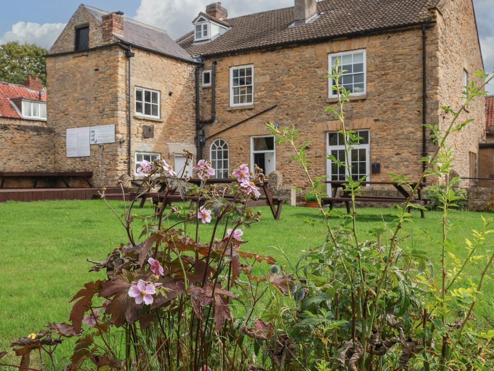 A garden with flowers and a building in the background at The Lodge in Snainton near Scarborough