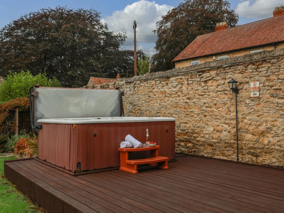 A jacuzzi on a wooden deck with towels and a table at The Lodge in Snainton near Scarborough