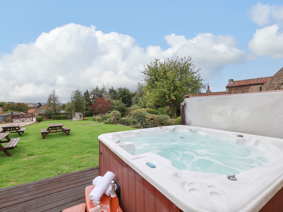 A garden with a hot tub and picnic tables at The Lodge in Snainton near Scarborough