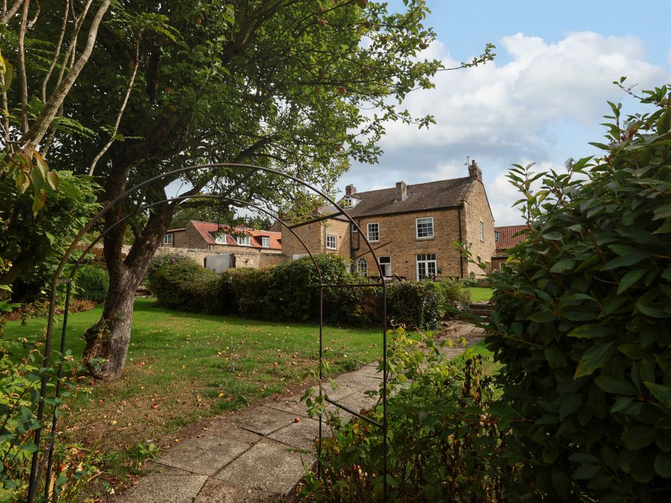 A garden with a house and pathway at The Lodge in Snainton near Scarborough