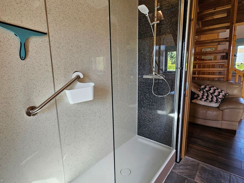 A shower with a grab bar and shower head at Orion Lodge Roy Bridge near Fort William